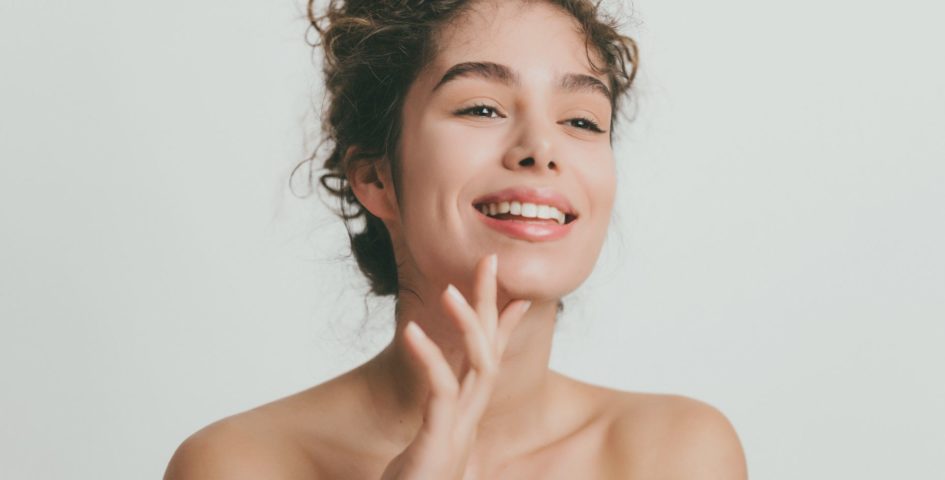 Rosto de mulher sorrindo, com a pele radiante e bem cuidada, indicando o uso de vitaminas para a pele.