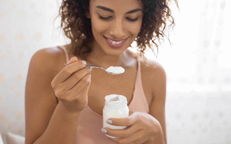 mulher come iogurte com probióticos